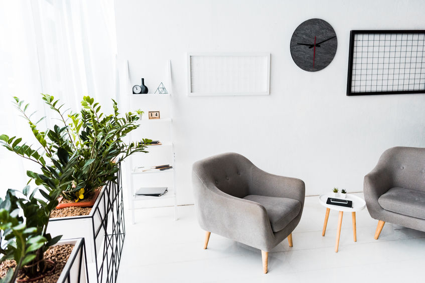 modern interior of waiting hall with grey armchairs and plants