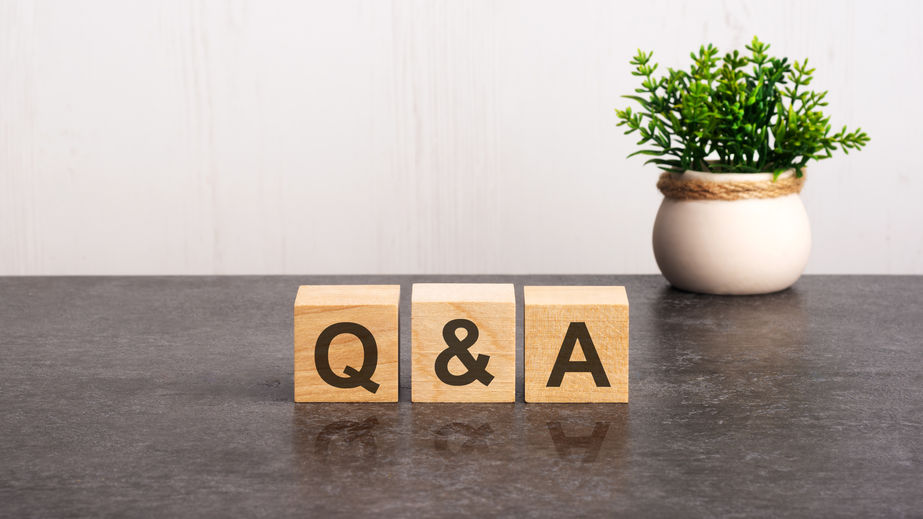 letters of the alphabet of Q and A on wooden cubes, green plant on a white background. Q and A - short for Question and Answer